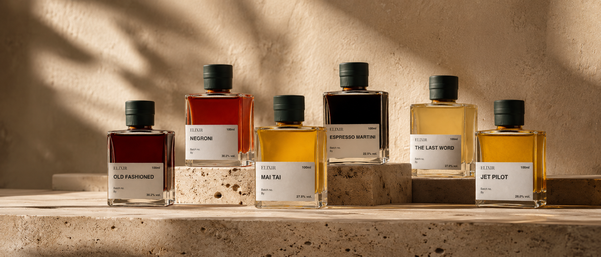 The six Elixir Bar bottled cocktails — Old Fashioned, Negroni, Mai Tai, Espresso Martini, The Last Word and Jet Pilot — arranged on warm travertine stone in soft daylight
